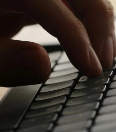 Close-up of a hand typing on a computer keyboard