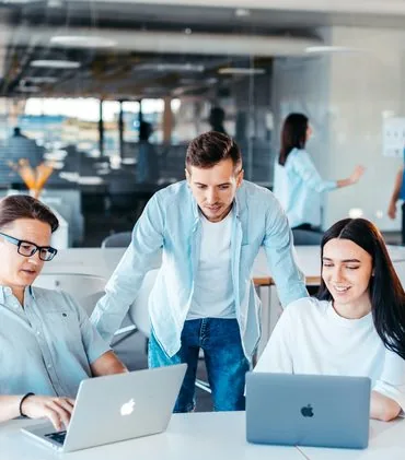Group of people sitting around a table working on laptops