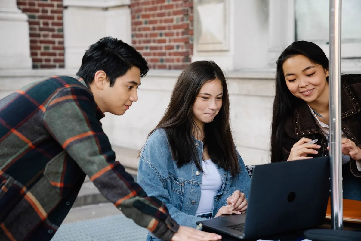 Students collaborating around a laptop on campus