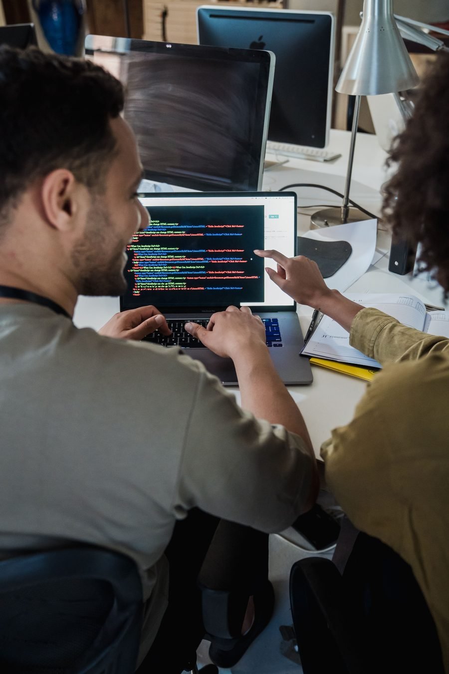 Two developers reviewing deployment code together on a laptop