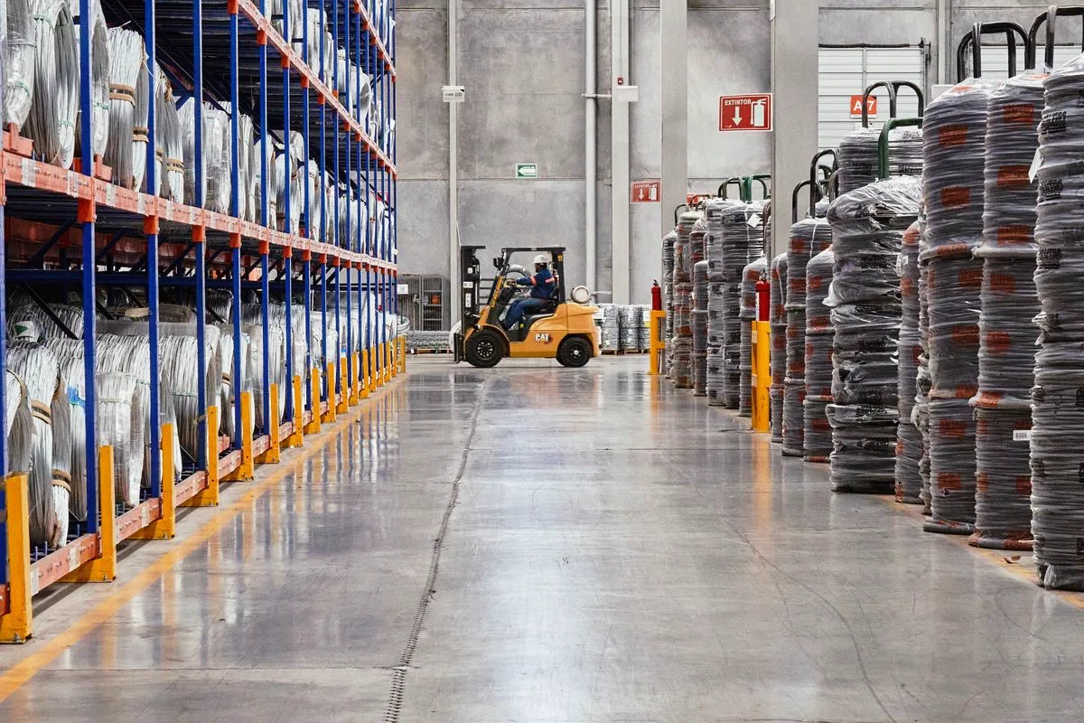 Warehouse associate operating a forklift among stacked inventory at a logistics depot