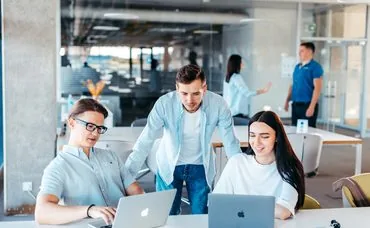 Group of people sitting around a table working on laptops