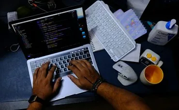 Hands typing on a laptop with code on the screen