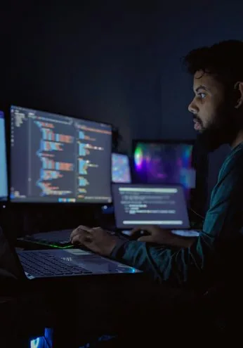 Developer sitting in front of three computer monitors